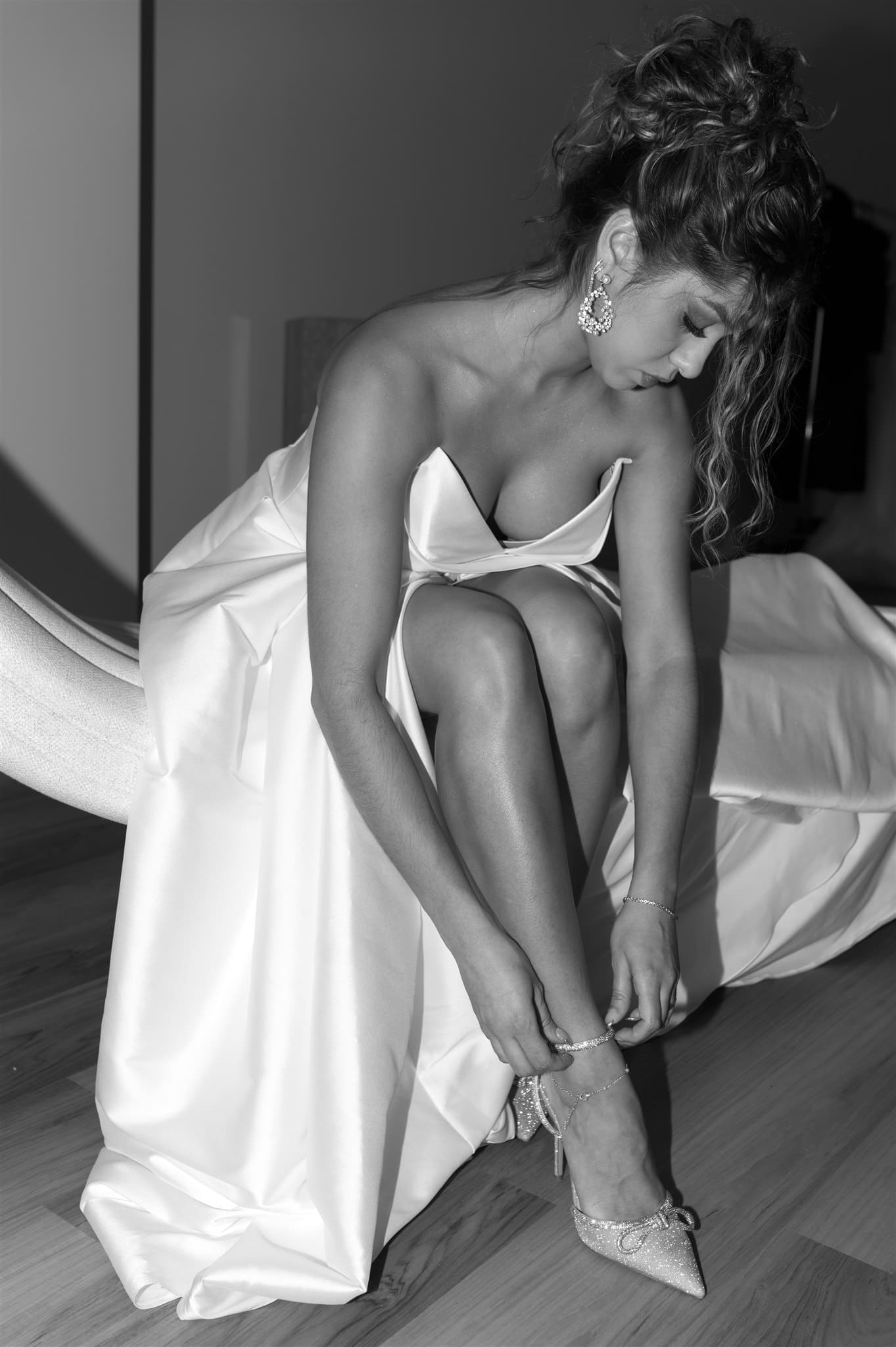 Bride adjusting her wedding shoes in an elegant satin gown in black and white