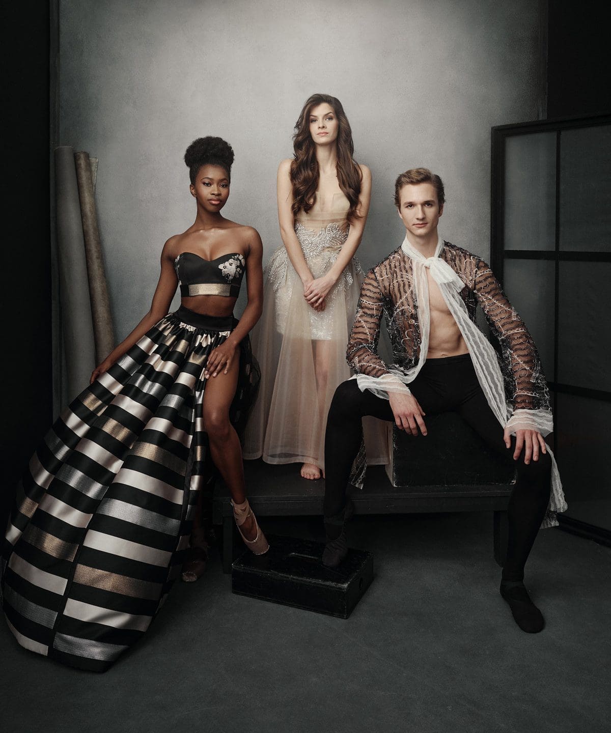 Three models posing in high-fashion couture outfits for an editorial photoshoot